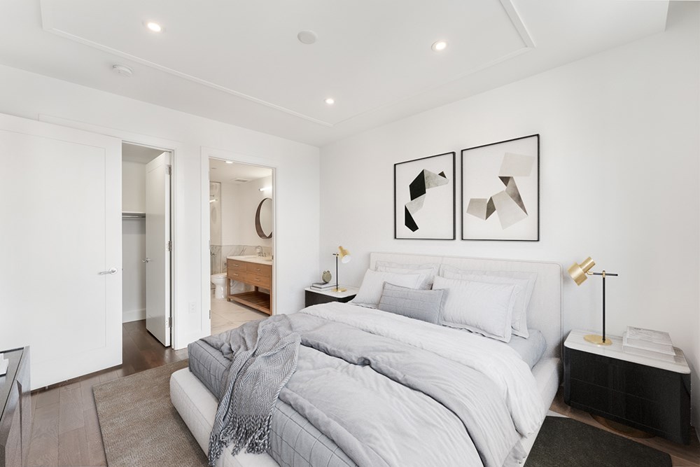 a white bedroom with a large bed and a bathroom